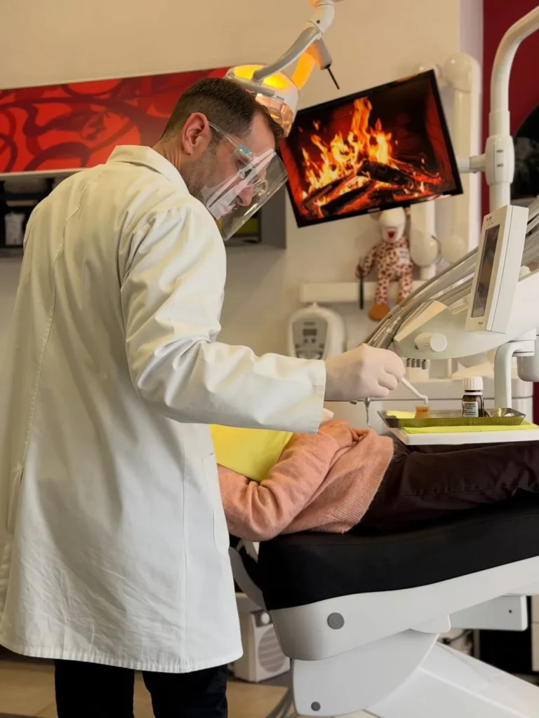 Médico dentista a atender uma paciente no gabinete, com um ecrã à frente da cadeira
